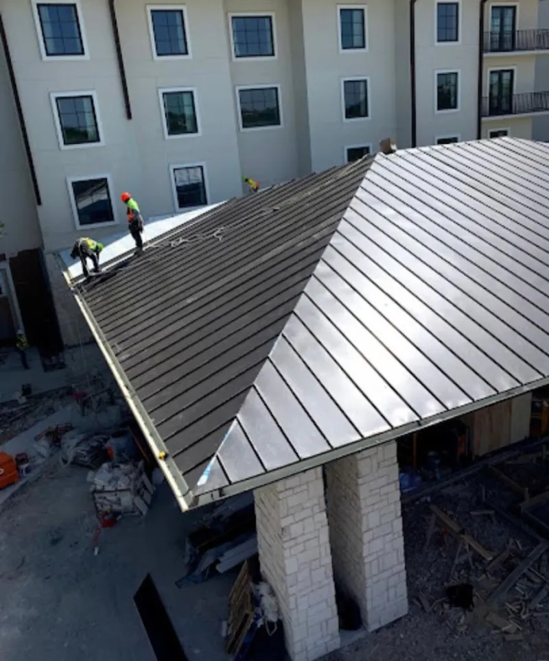 Crew installing standing seam metal roof panels on a commercial project in Shrewsbury